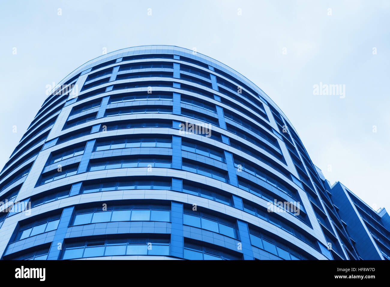 Edificio de oficinas de cristal azul sobre fondo de horizonte de rascacielos Foto de stock