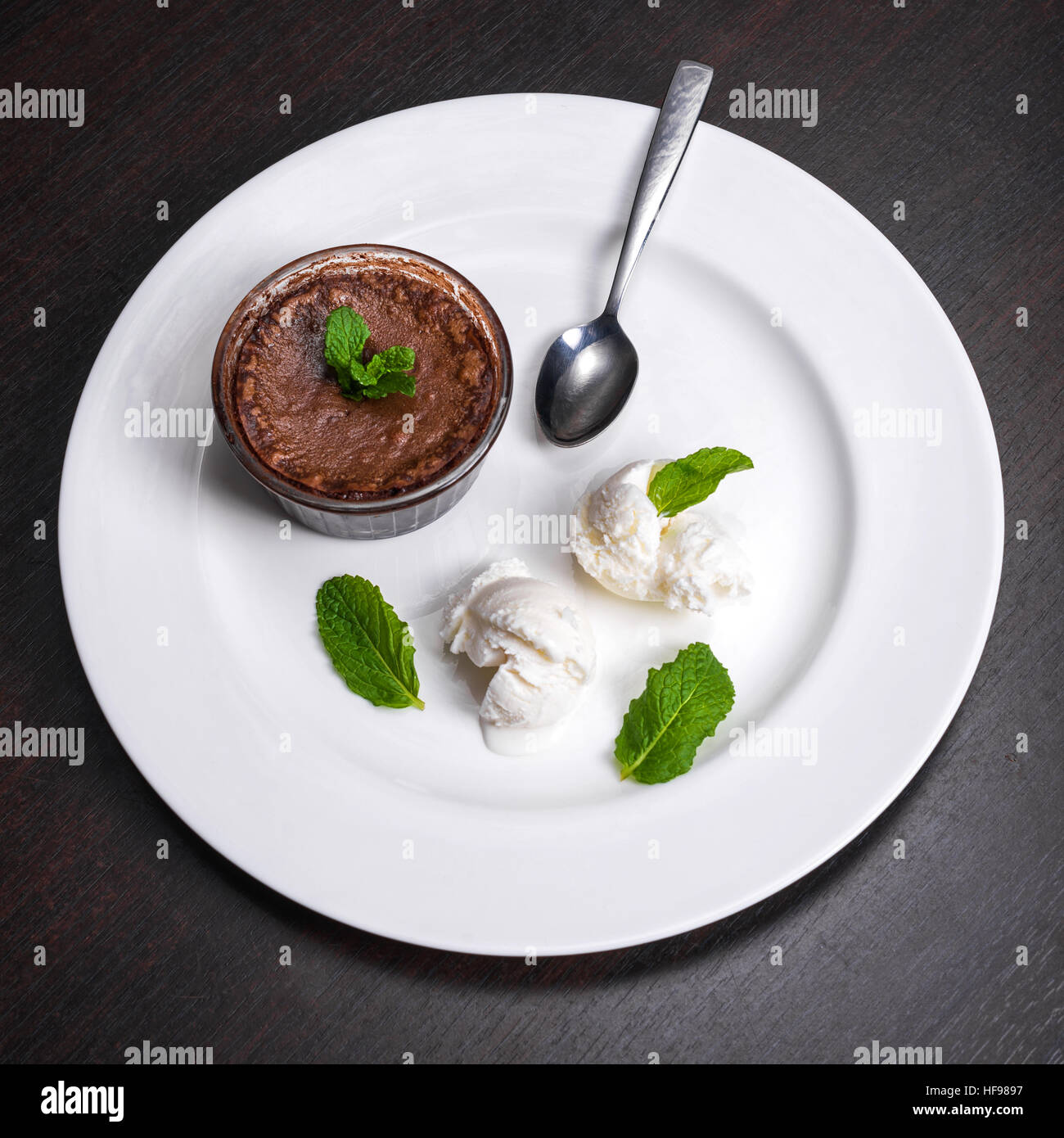 Fondant de chocolate caliente postre torta de lava servido con bolas de  helado de vainilla y menta en la placa blanca. Famoso postre francés sobre  la mesa de madera oscura vista superior