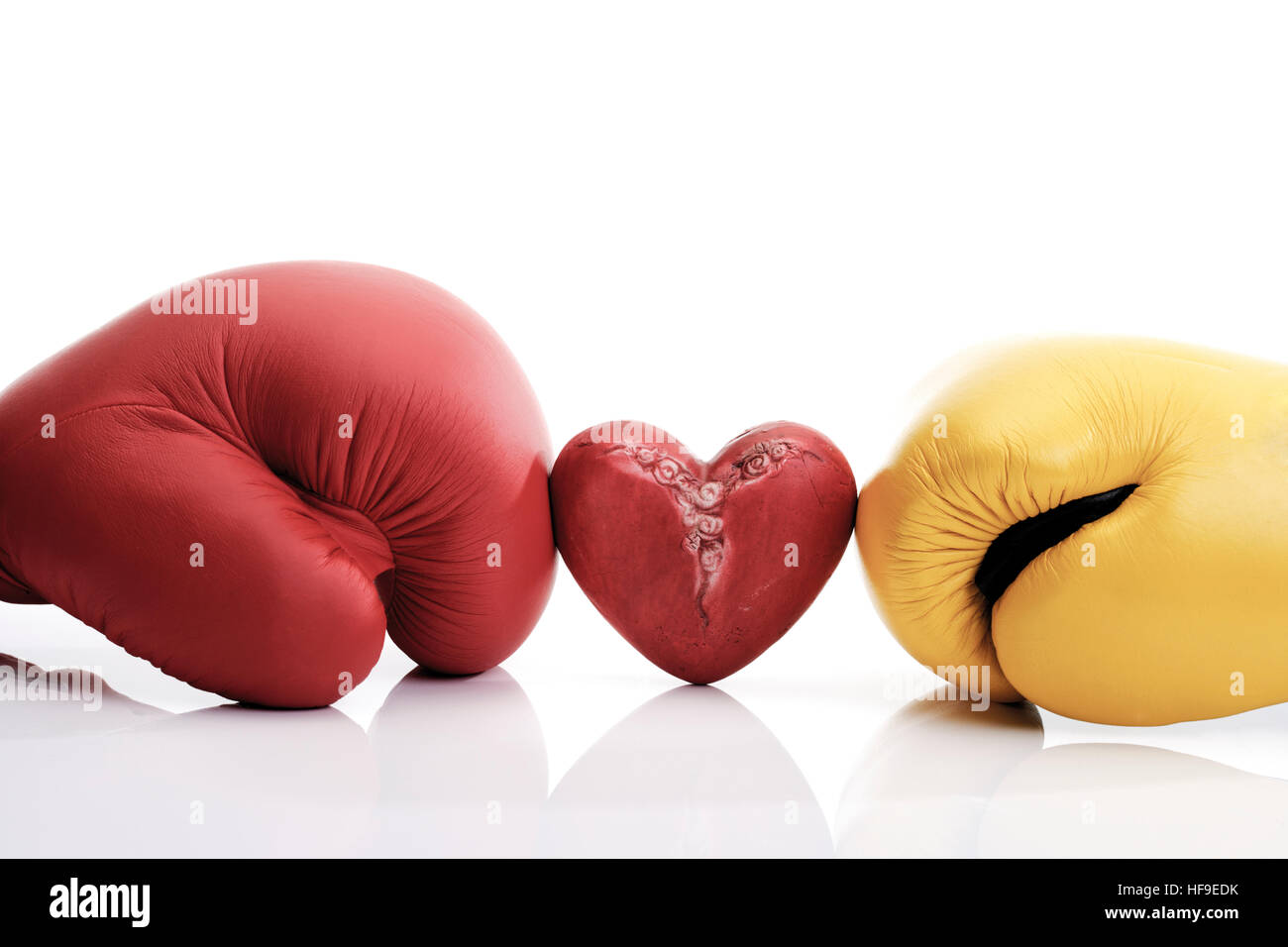 Corazón rojo atrapado entre el amarillo y el rojo Guantes boxeo: la lucha por el amor Foto de stock