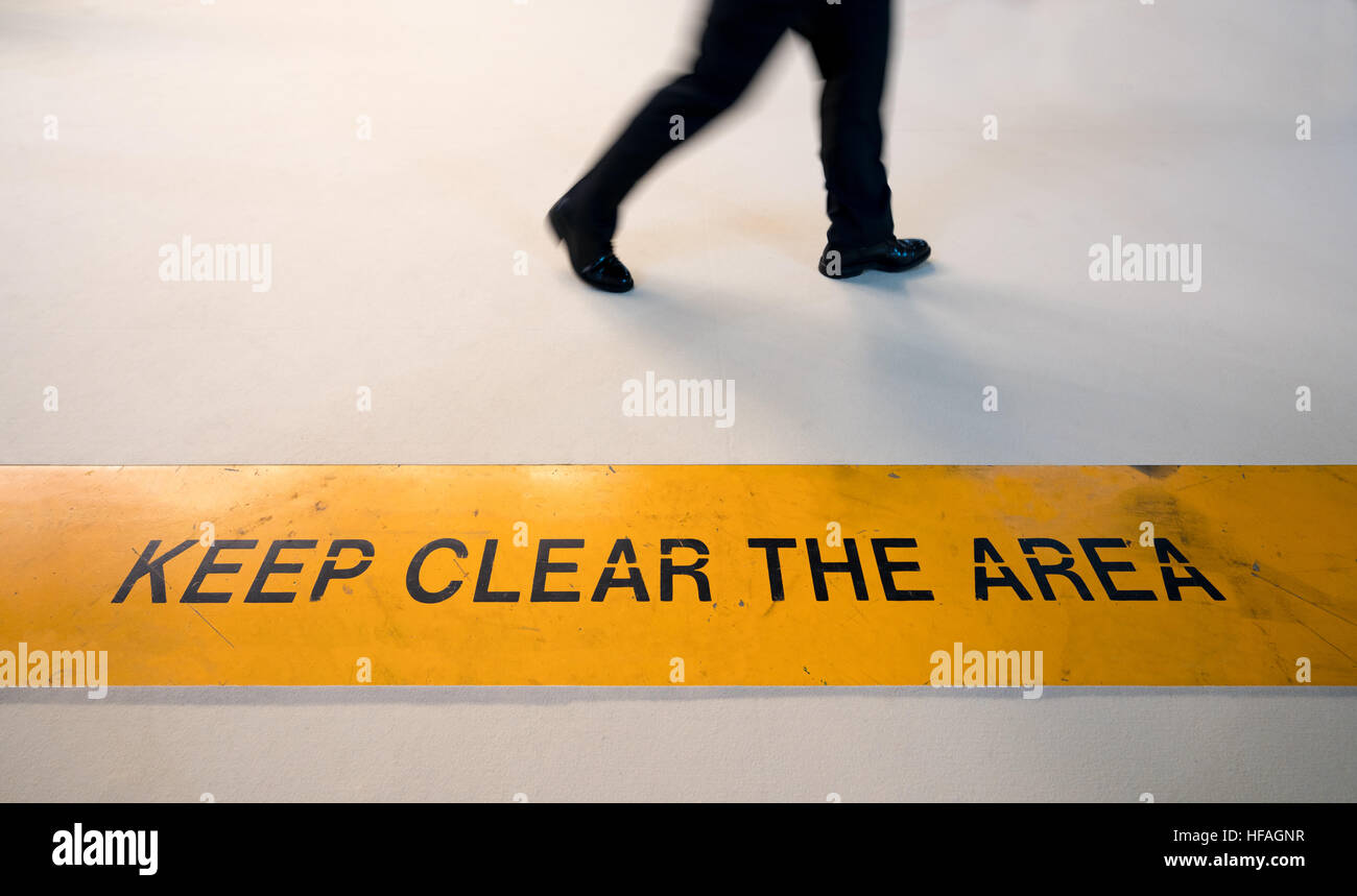 Hombre caminando en zona prohibida con el desenfoque de movimiento, rompiendo la noción de regla, mantener señal clara sobre el piso con espacio de copia Foto de stock