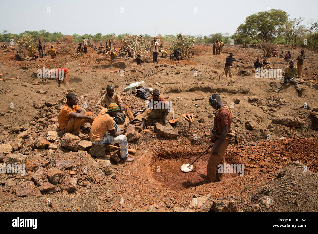 Mina de Oro Sanana, Guinea, el 2 de mayo de 2015; mineros cavan mientras otros pagan a un hombre con un detector de metales para verificar su tierra. Foto de stock
