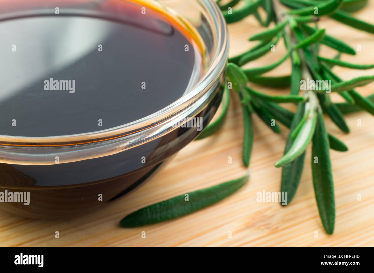 Desenfoque de imagen borrosa y la salsa de soja en un vaso y una ramita de romero sobre una plancha de madera desc Foto de stock