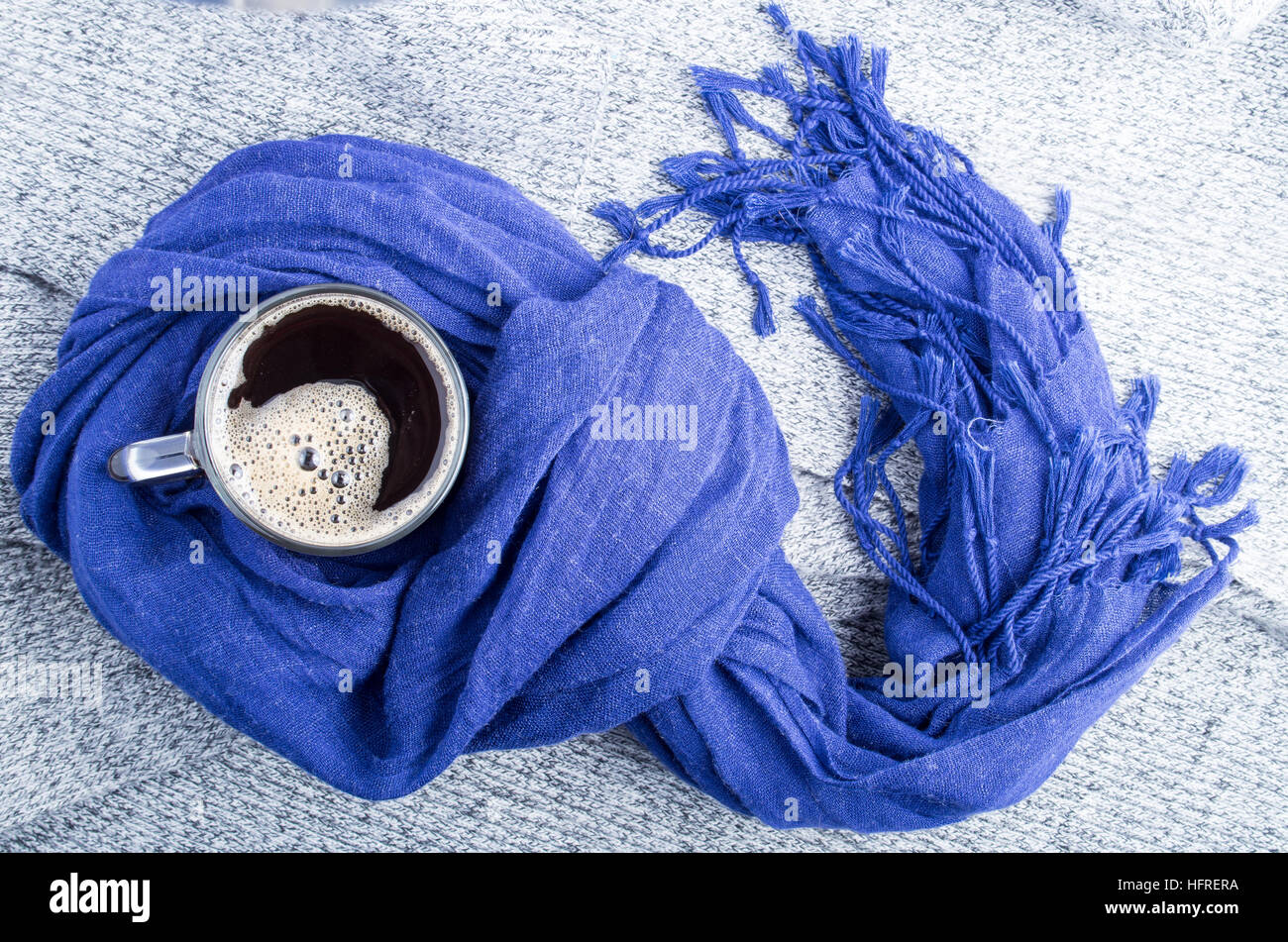 Algodón azul pañuelo atado en un nudo alrededor de la taza de café caliente sobre un fondo gris Foto de stock