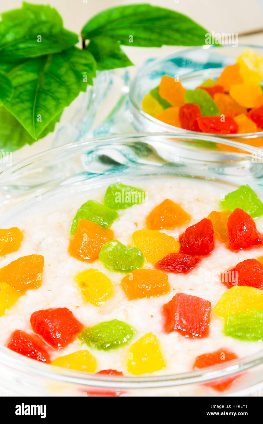 Ver de cerca en la avena con colorido las frutas confitadas en un tazón de vidrio sobre la mesa para un desayuno saludable con poca profundidad de campo. Foto de stock