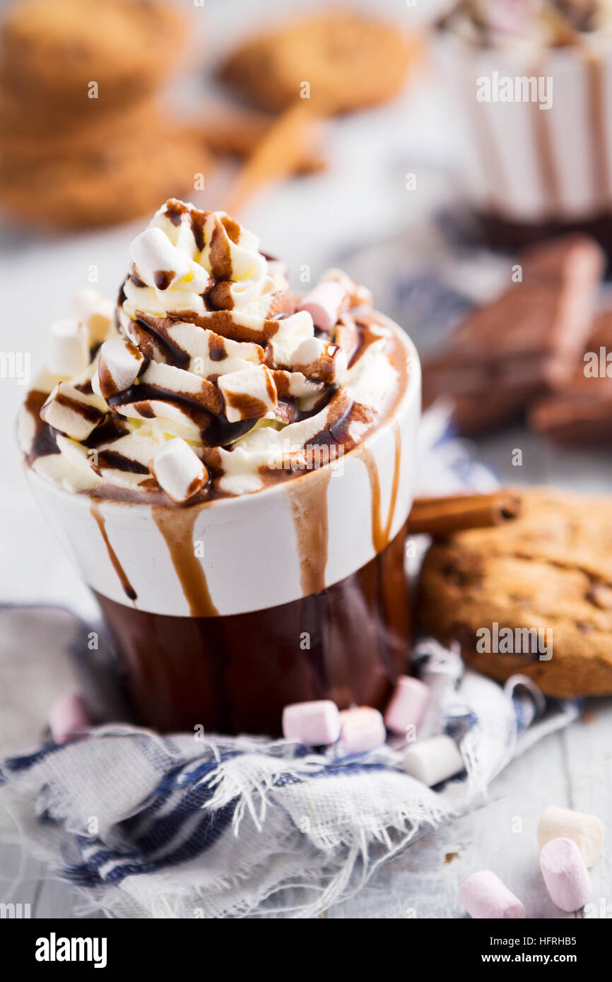 Un confuso taza de chocolate caliente, crema batida, malvaviscos y galletas con trocitos de chocolate. Foto de stock