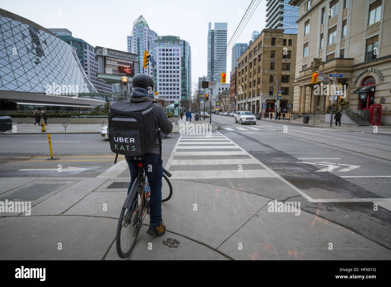 TORONTO, Canadá - 31 de diciembre de 2016: Uber come hombre entrega sobre una bicicleta esperando para cruzar una calle Foto de stock