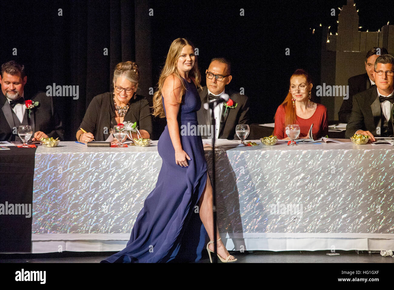 Los jueces del concurso de belleza ojo un concursante vestido formalmente como ella camina por su tabla en Huntington Beach, California. Foto de stock