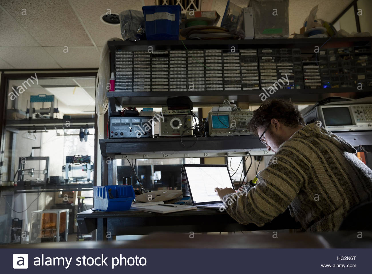 Programador que trabaja en equipo portátil en taller oscuro Foto de stock