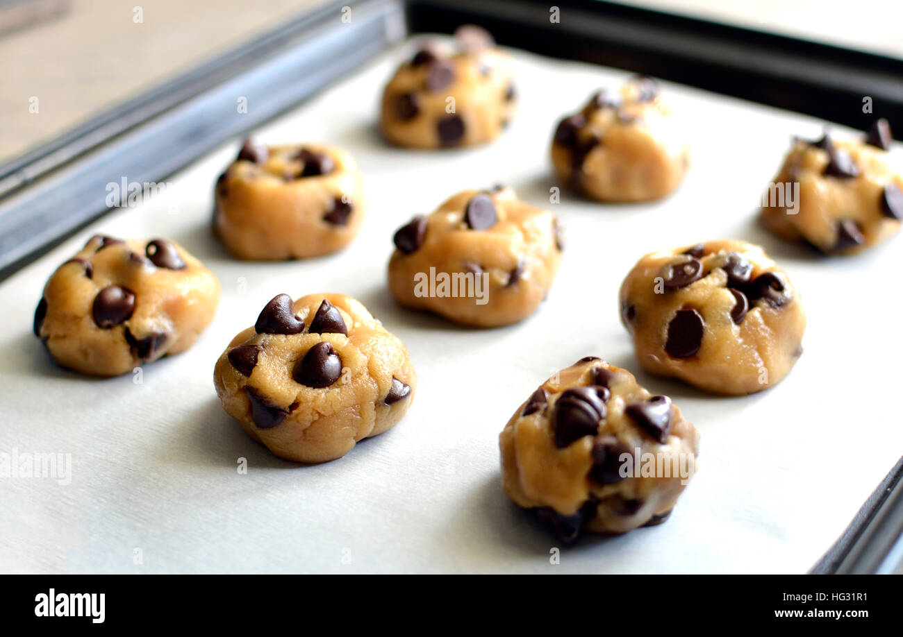 Masa de galletas con trozos de chocolate en la bandeja para hornear Foto de stock