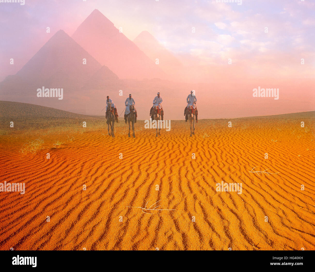Las pirámides y los cuatro jinetes de camellos al amanecer en la meseta de Giza, Cairo, Egipto Foto de stock