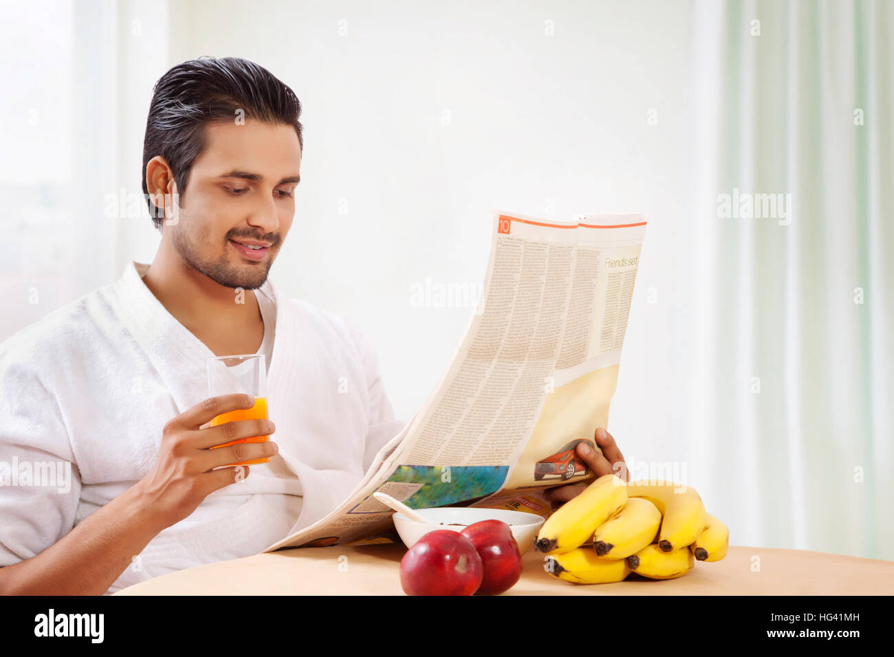 Retrato del hombre leyendo un periódico a la mesa de desayuno Foto de stock