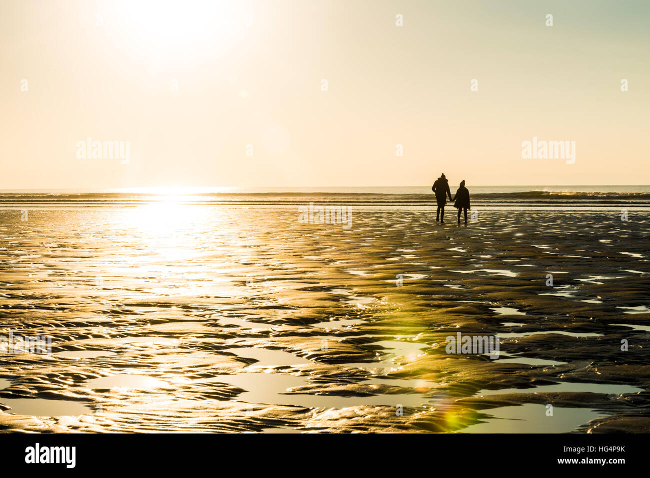 Una pareja caminando por la playa por la noche Foto de stock