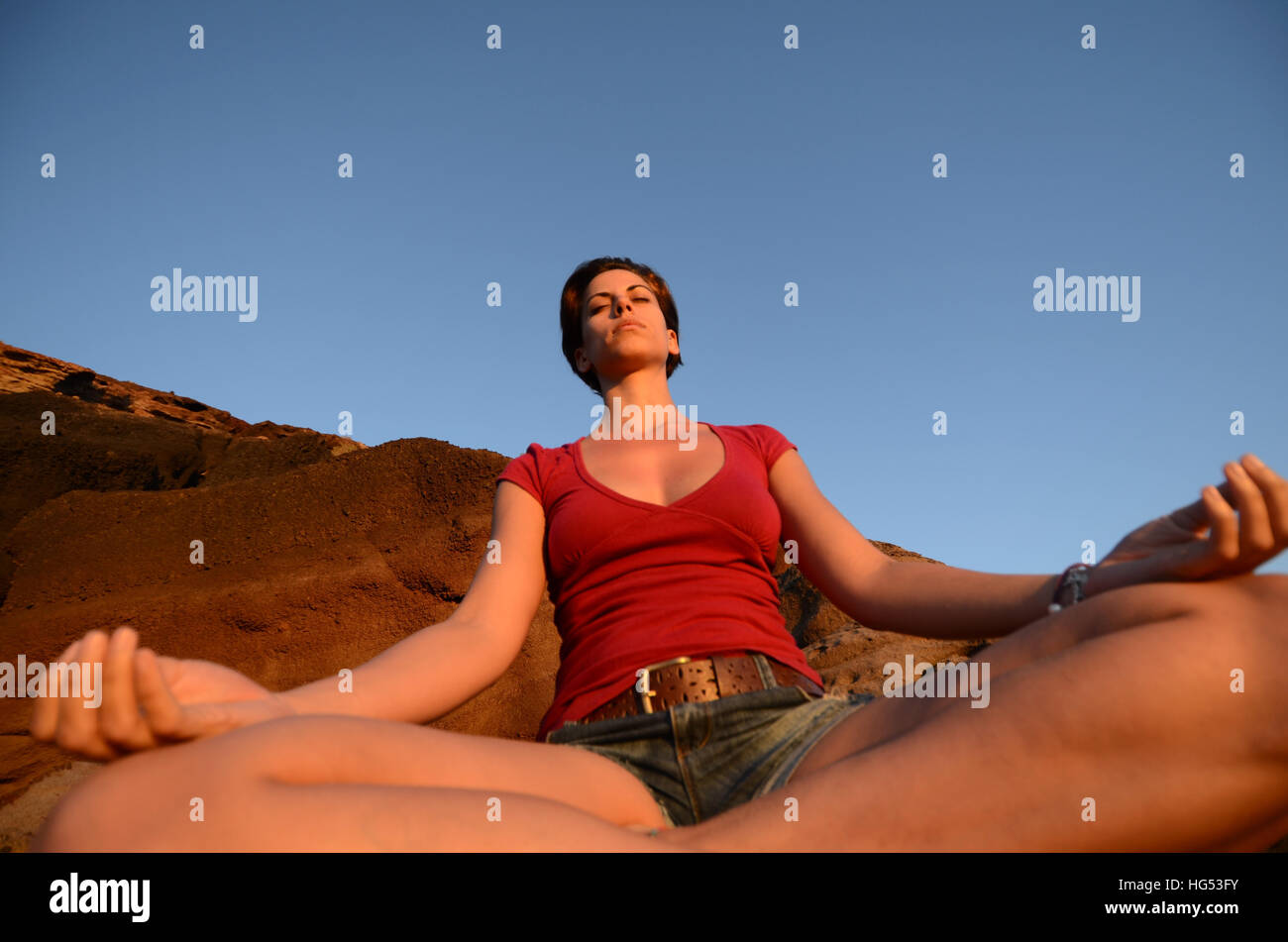 Atractiva mujer joven medita en lotus plantear, frente a la costa. Foto de stock