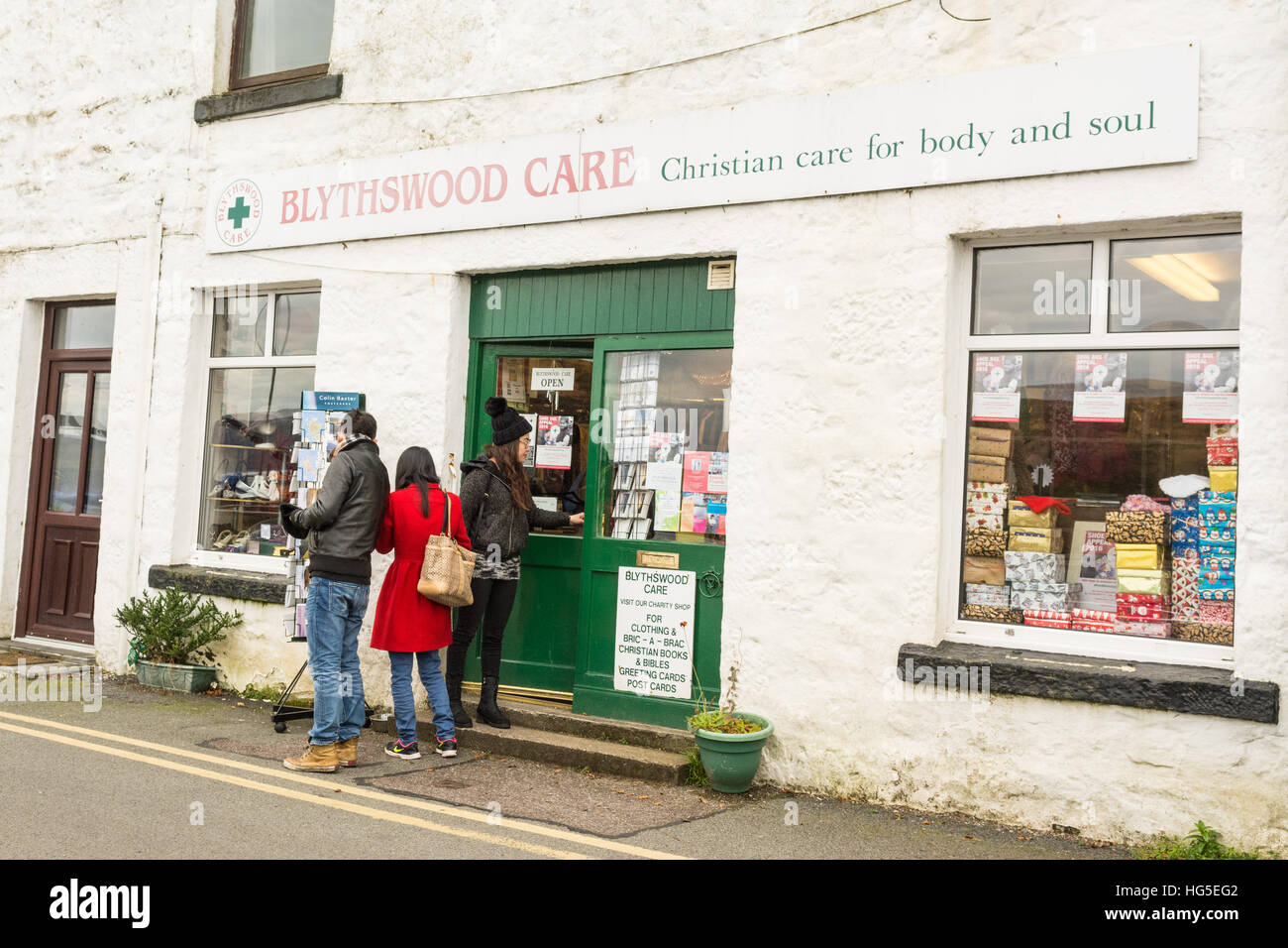 Los turistas fuera de la caridad cristiana de atención Blythswood shop - Portree Harbourfront, Isla de Skye, Escocia, Reino Unido Foto de stock