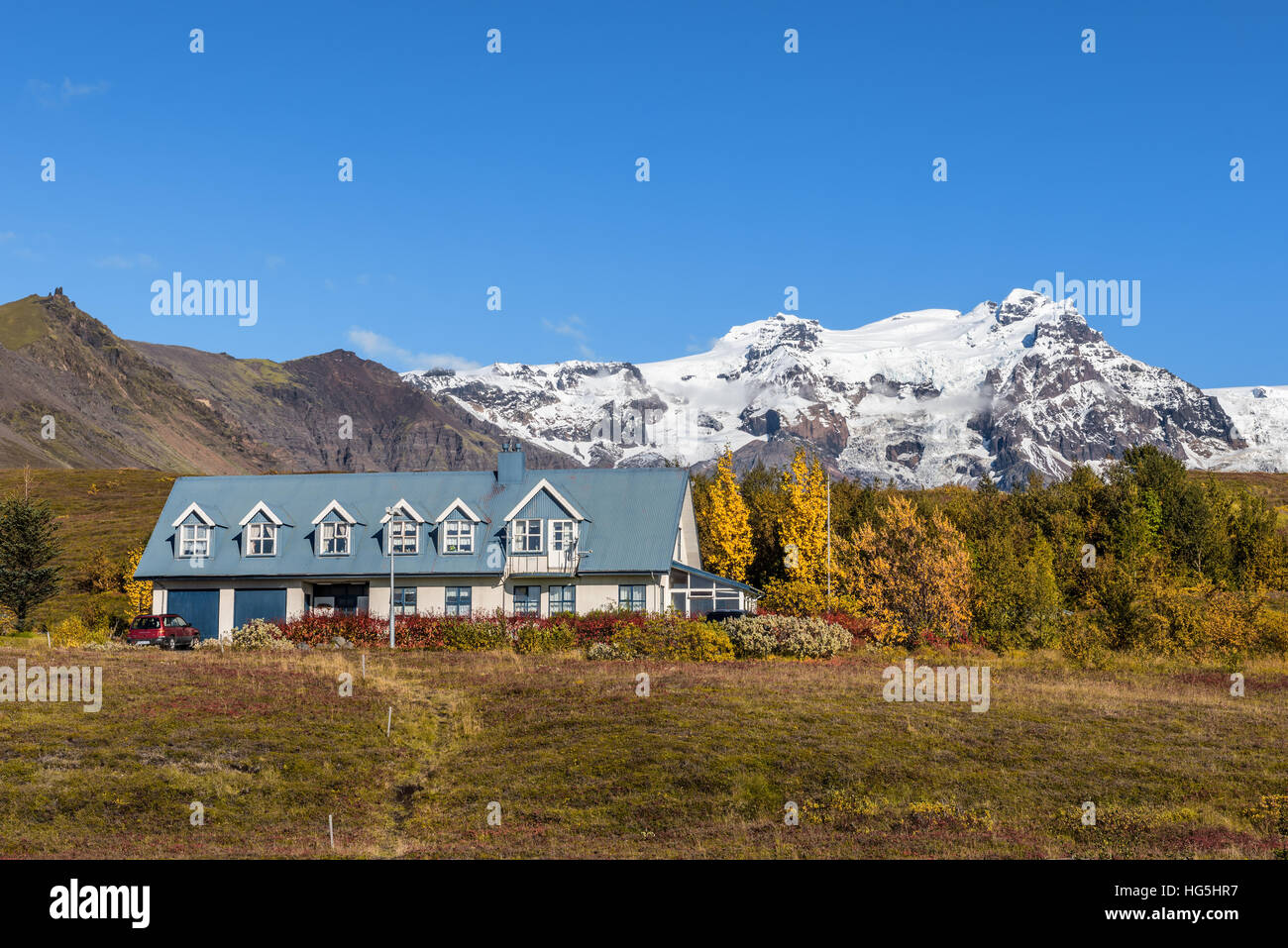 Paisaje con una casa de Islandia y montañas nevadas en el fondo. Foto de stock