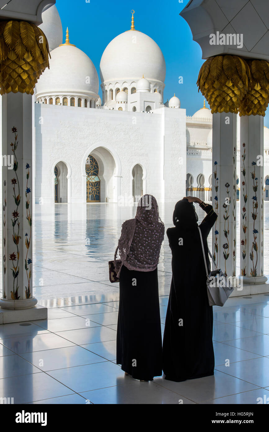 Dos mujeres del Medio Oriente tradicionalmente vestidos viendo la Mezquita Sheikh Zayed, Abu Dhabi, Emiratos Arabes Unidos Foto de stock
