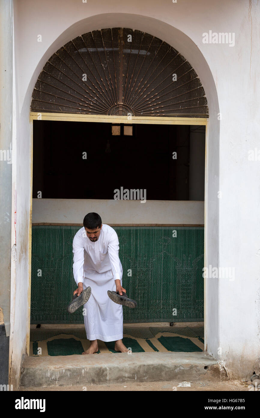 El Ksar Elkhorbat, Marruecos. Hombre quitando los zapatos antes de entrar a la mezquita. Foto de stock