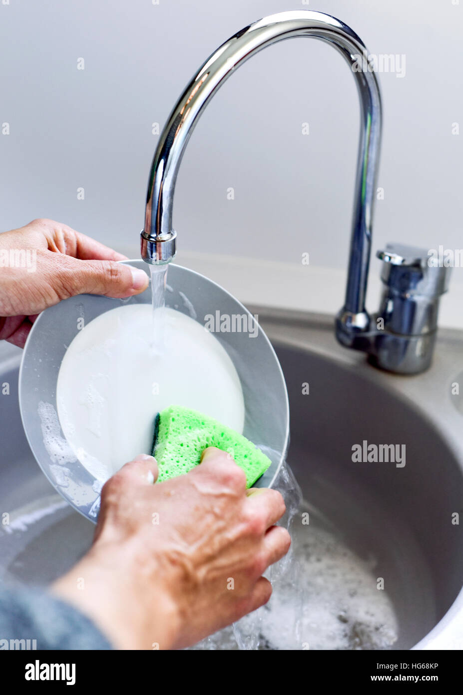 https://c8.alamy.com/compes/hg68kp/primer-plano-de-un-joven-lavando-platos-en-un-fregadero-con-una-esponja-verde-hg68kp.jpg