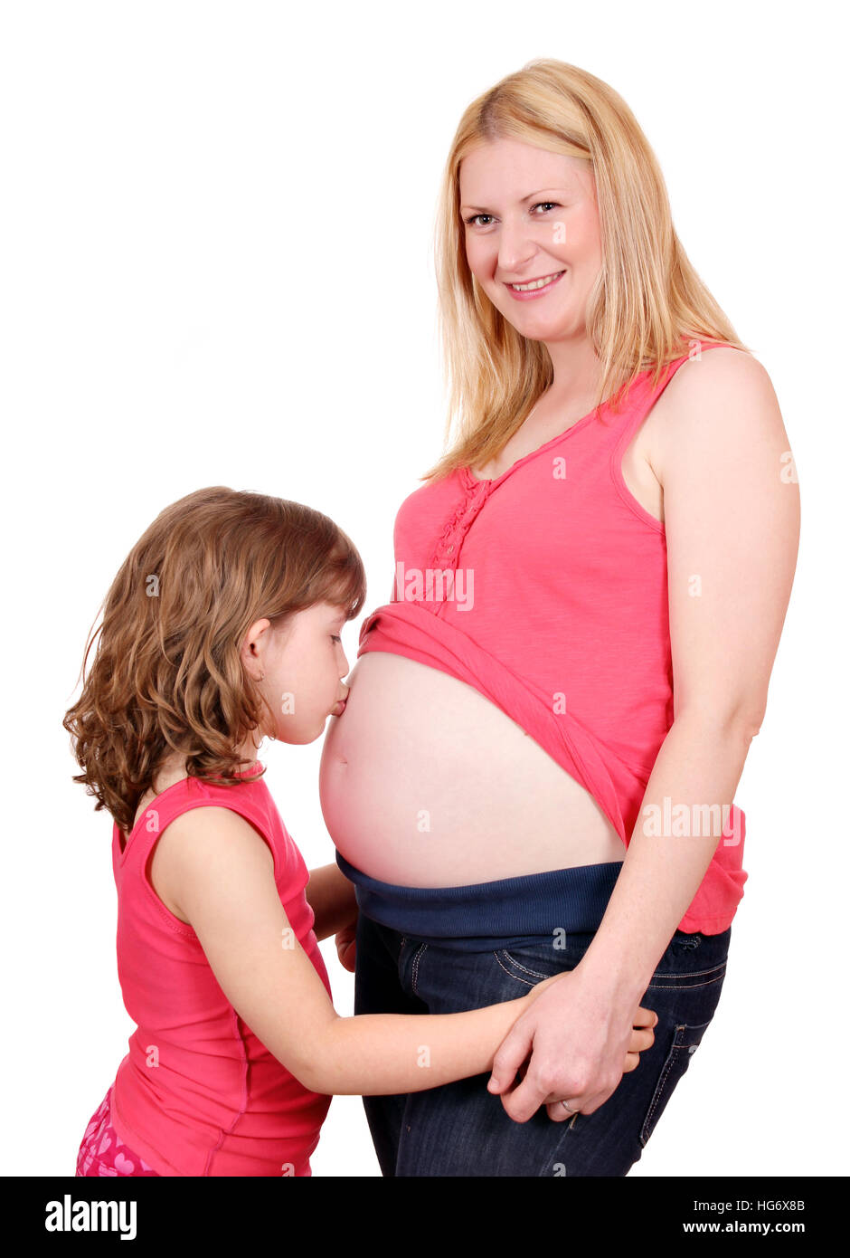 Niña besando el vientre de la mujer embarazada Foto de stock