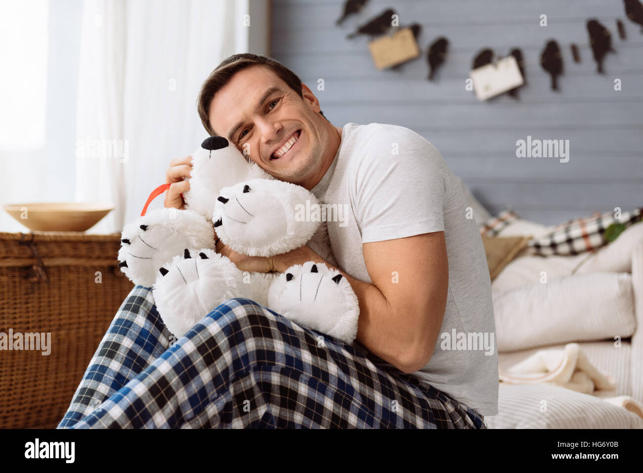 Feliz hombre alegre abrazando un peluche Foto de stock