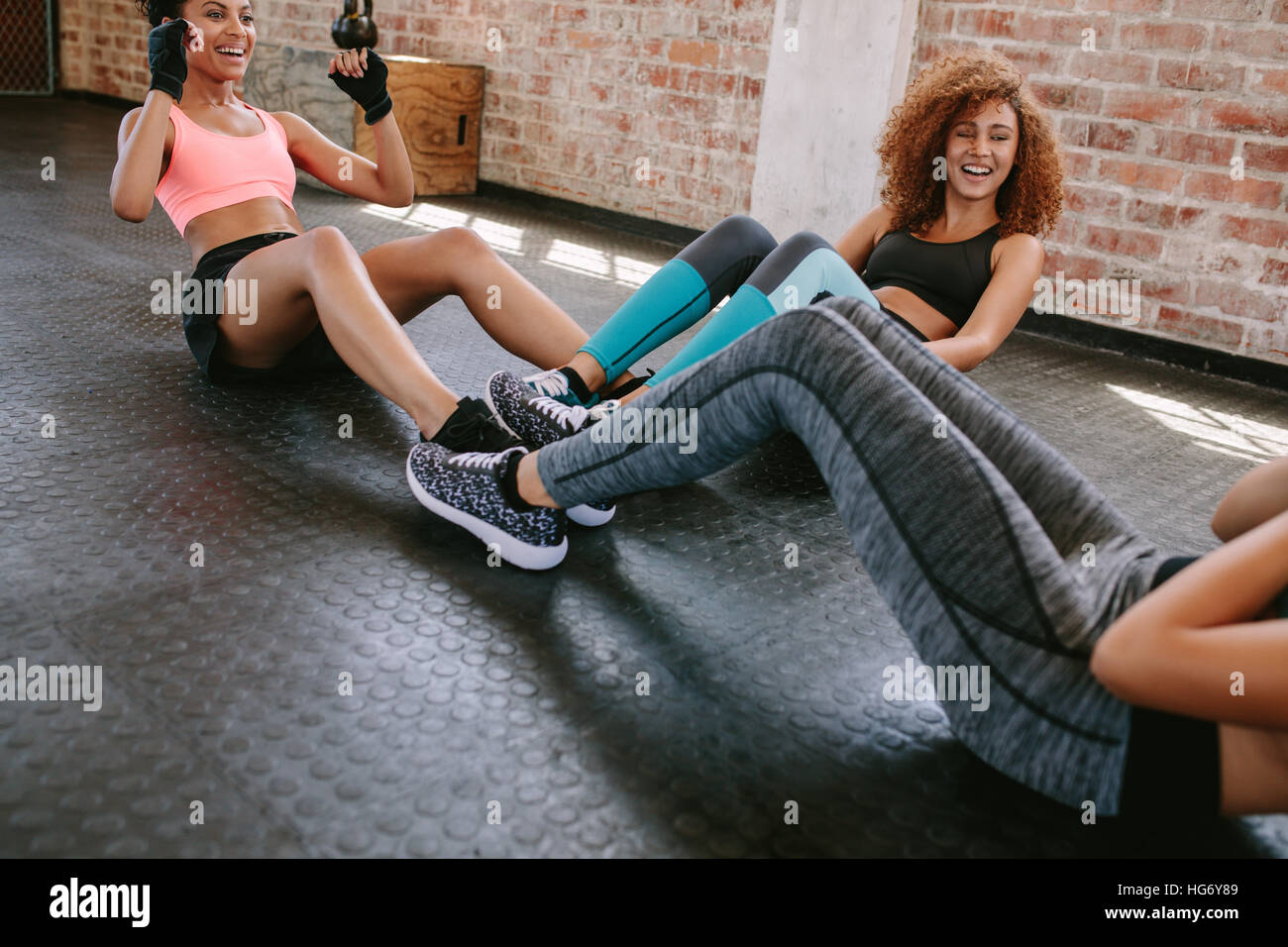 Grupo de mujeres ejercitarse en el gimnasio. Tres joven haciendo situps juntos en el gimnasio. Foto de stock