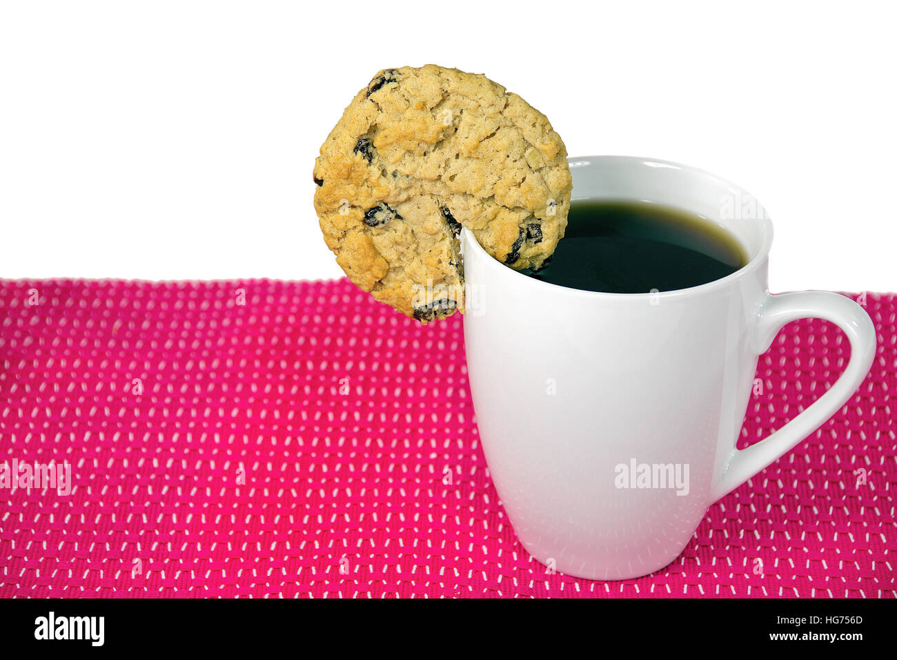 Galletas de harina de avena con pasas en el aro de taza blanca con café negro Foto de stock