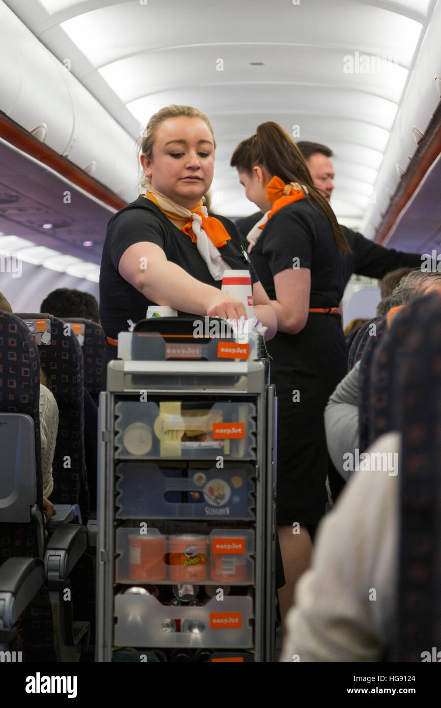 La tripulación de cabina / aire azafata sirve bebidas y bocadillos a los pasajeros - & toma pago - desde un carrito Carrito durante el vuelo de Easyjet Foto de stock