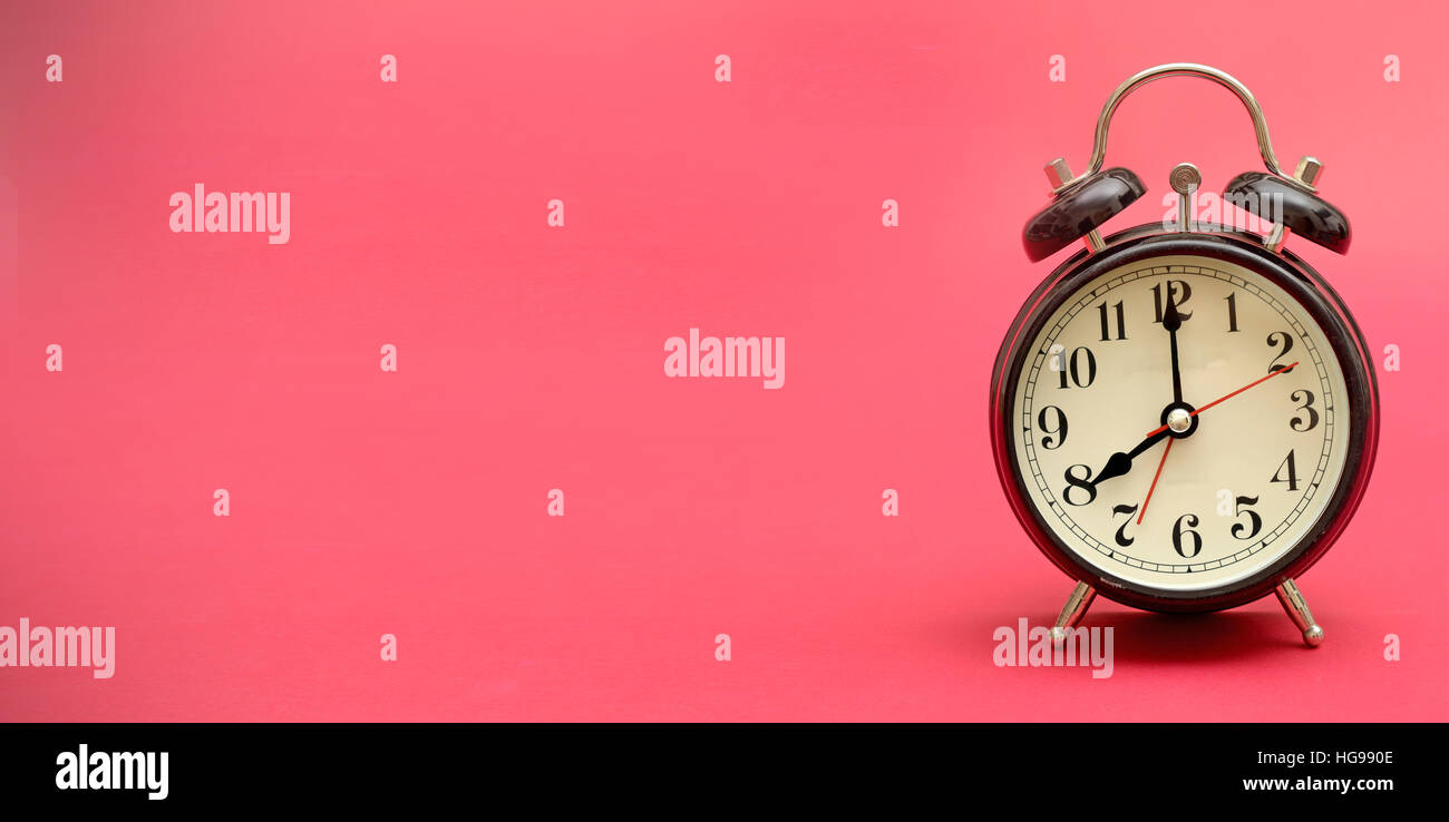 Antiguo reloj despertador retro en banner rosa con espacio de copia. Foto de stock