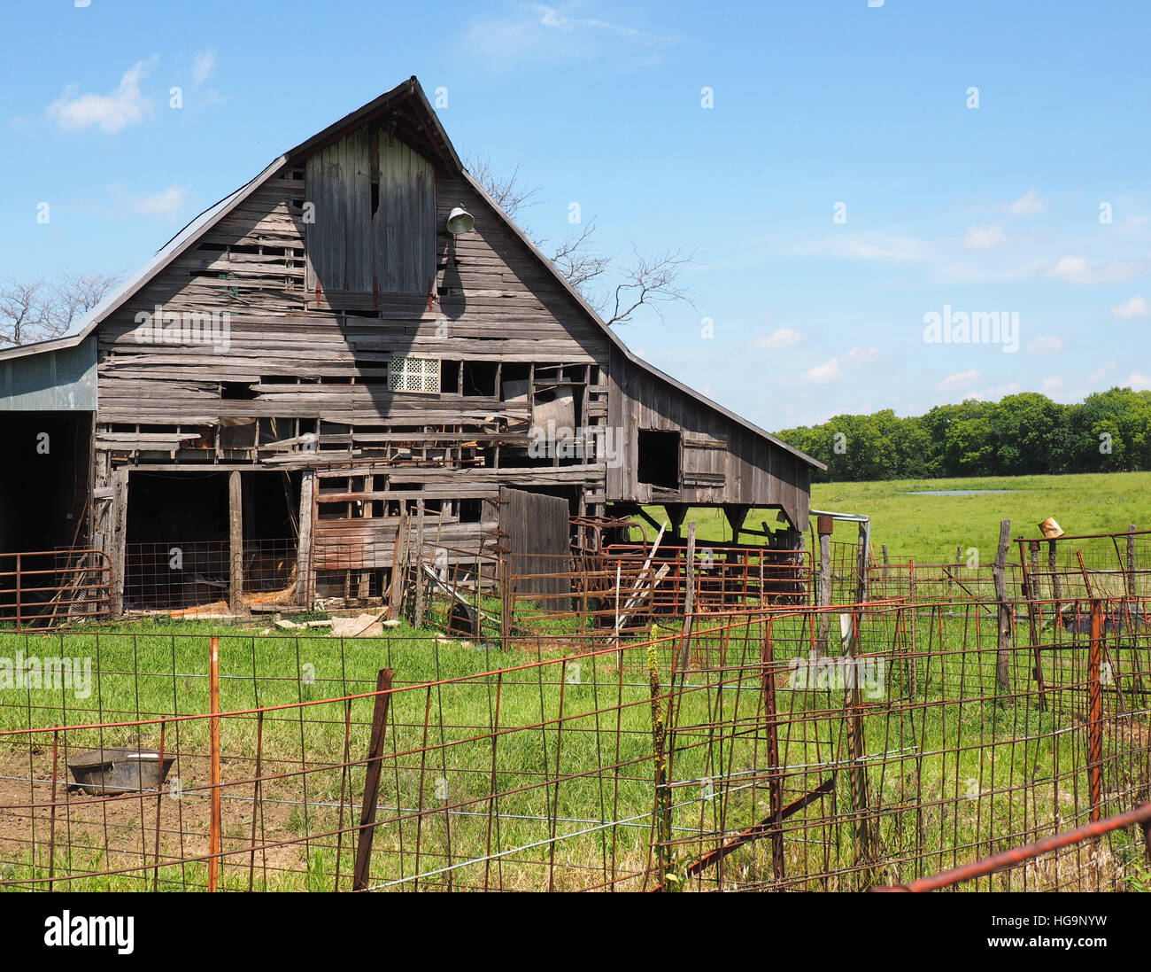Antiguo granero de madera por una valla oxidada en las zonas rurales de Kansas Foto de stock