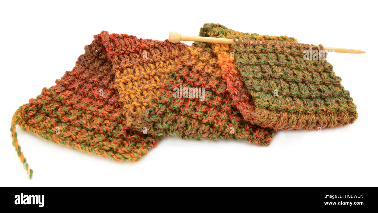 Longitud de tejido para una bufanda de colores otoñales en una aguja de tejer, aislado en un fondo blanco. Foto de stock