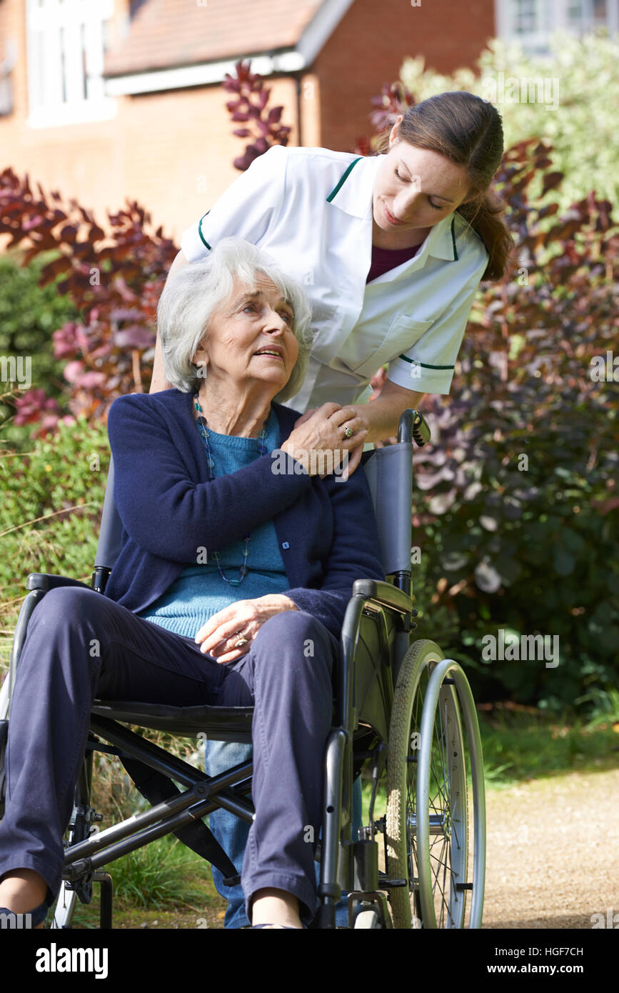 Cuidador empujando mujer mayor en silla de ruedas Foto de stock