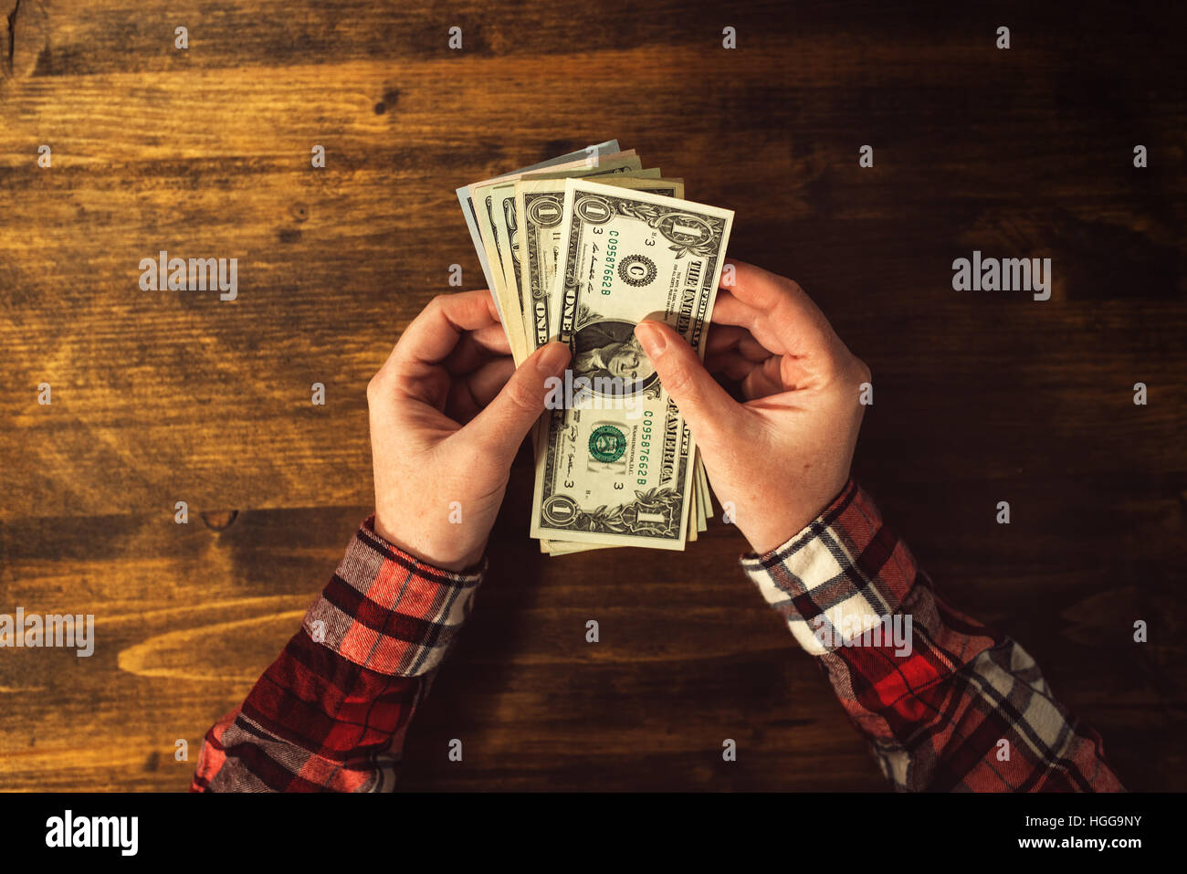 Vista superior de manos femeninas con billetes de dólar estadounidense a través de la oficina de madera Foto de stock