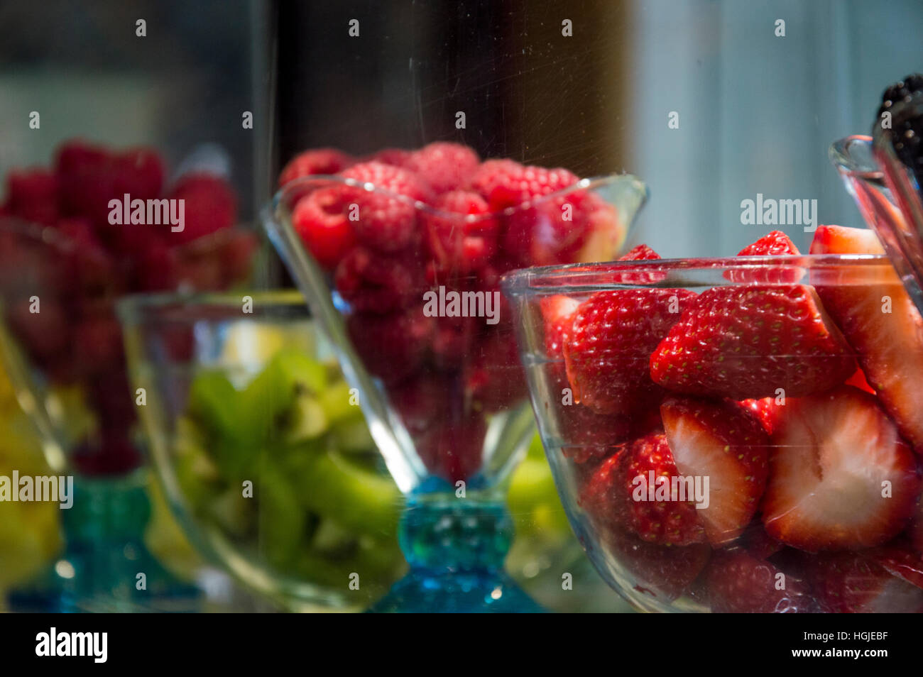 Flan de frambuesa, fresa fruta kiwi afrutado fresco sudor de vidrio en el mercado de alimentos gelateria Foto de stock
