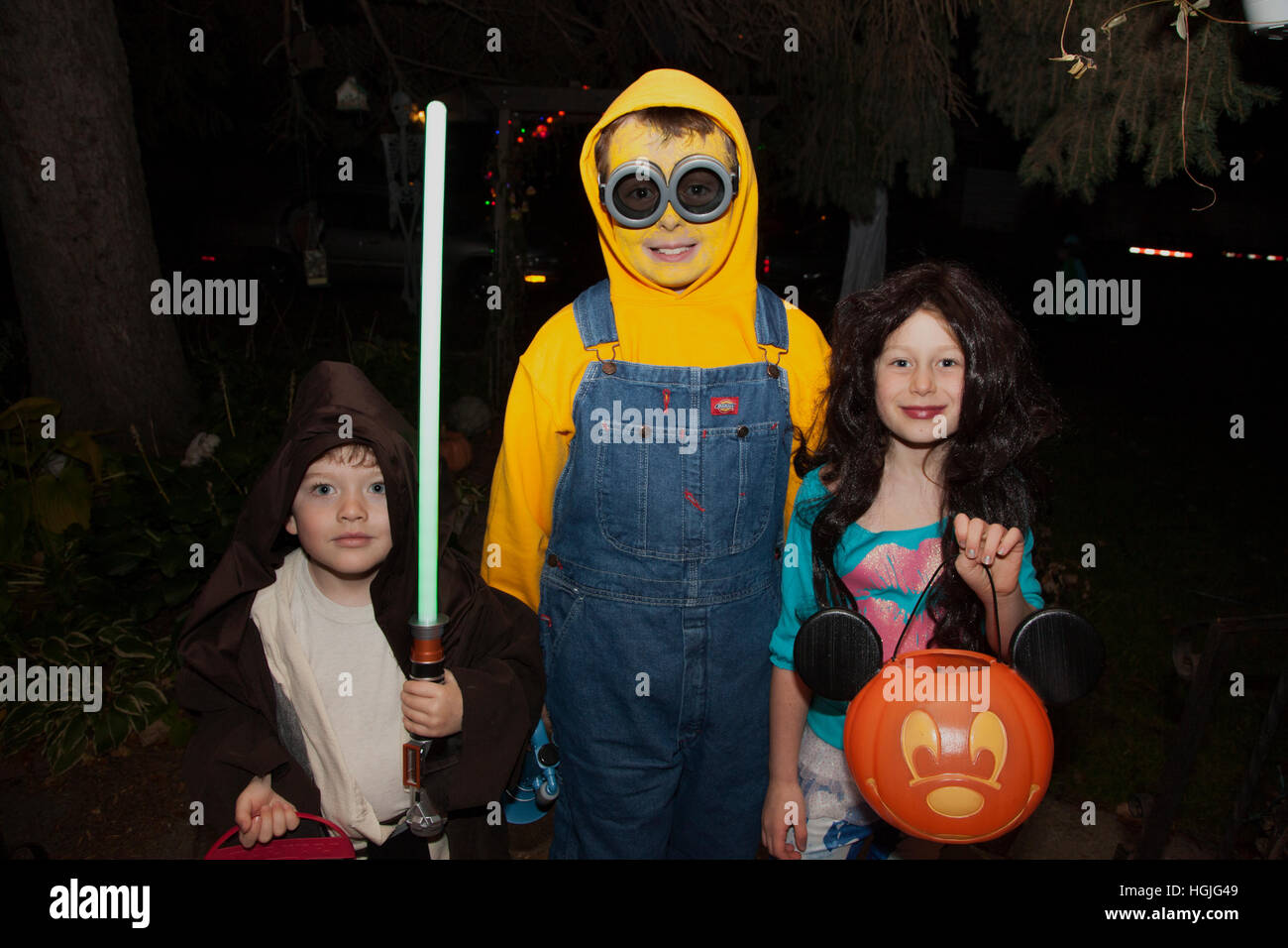 Halloween trick or treat los niños en esbirro y trajes Jedi Knight llevando un jack-o'-lantern de golosinas. St Paul MN Minnesota EE.UU. Foto de stock