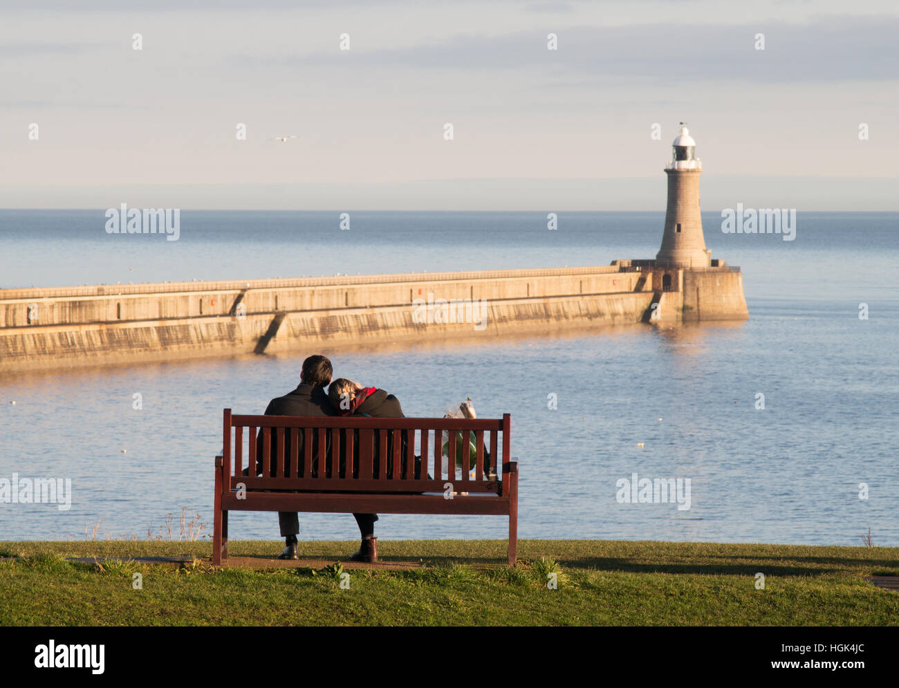 Par Sentados muy juntos en un banco mirando al mar del Norte,Tynemouth, North Tyneside, Inglaterra, Reino Unido. Foto de stock