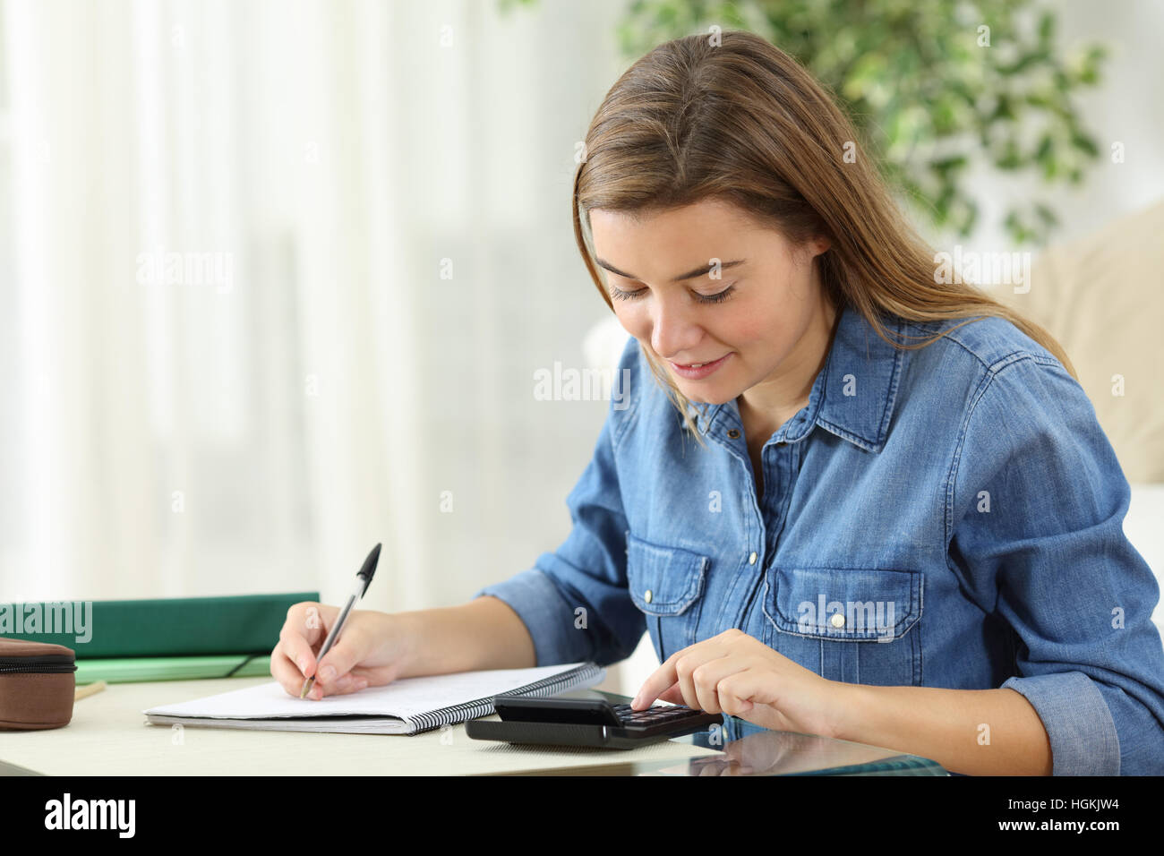 Estudiante de cálculo con una calculadora y escribir notas a mano el emplazamiento en el suelo del salón en casa Foto de stock