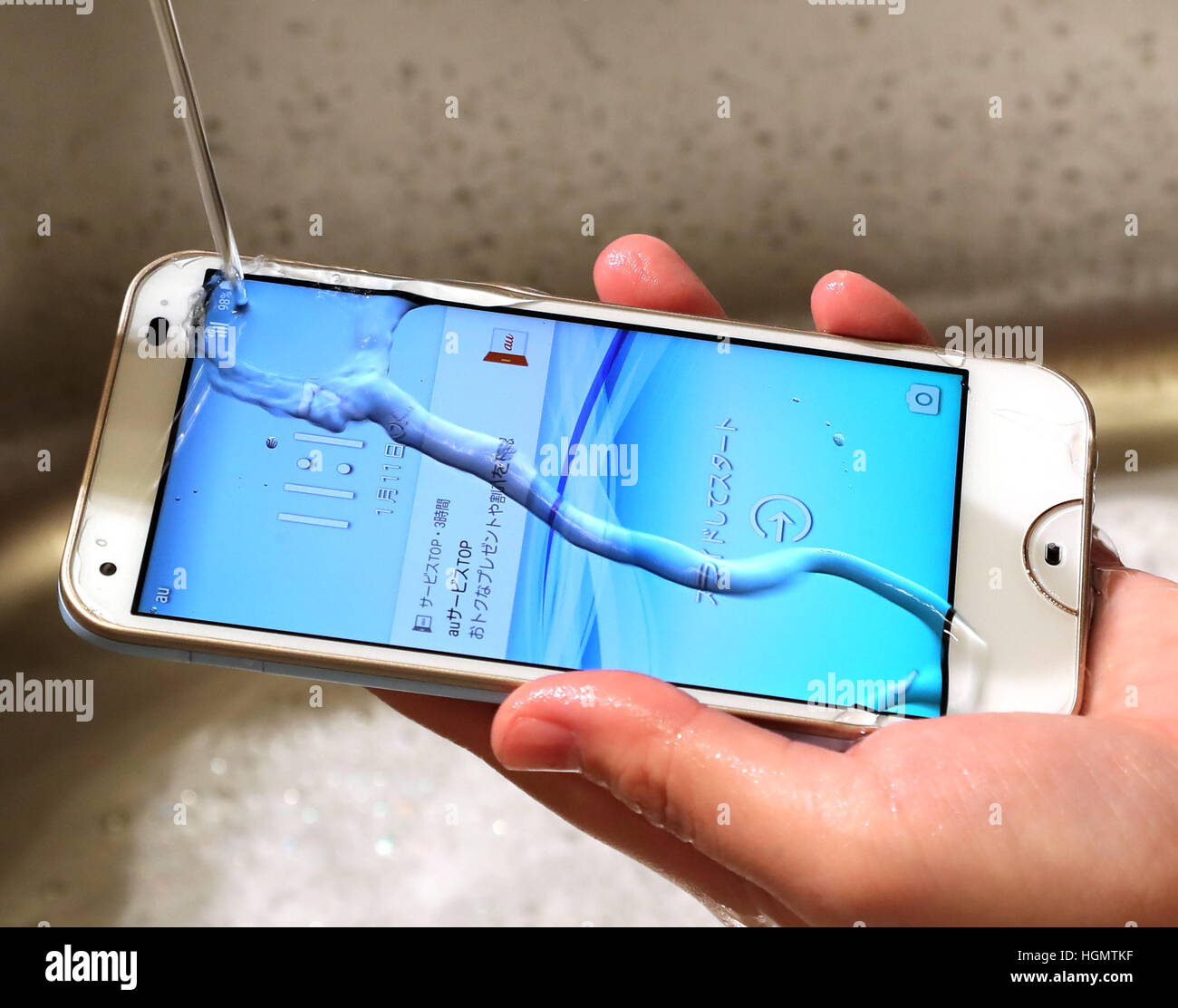 Tokio, Japón. 11 ene, 2017. Un modelo muestra la nueva agua y jabón-prueba  smart phone 'rafre', producido por Kyocera como parte del Japón el gigante  de telecomunicaciones KDDI la nueva línea de