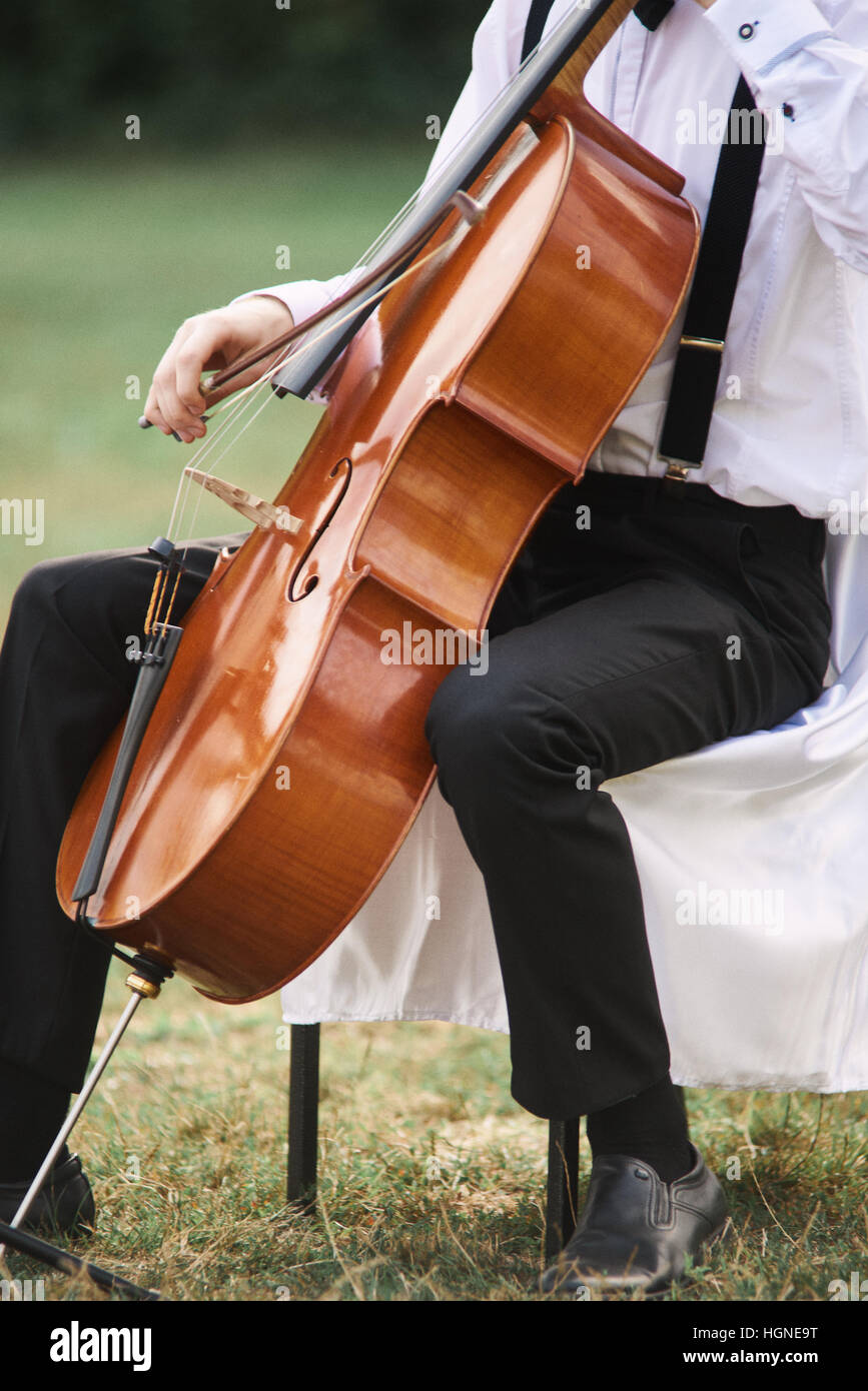 Joven tocando el violonchelo en el exterior. La violonchelista tocando música clásica en el cello Foto de stock