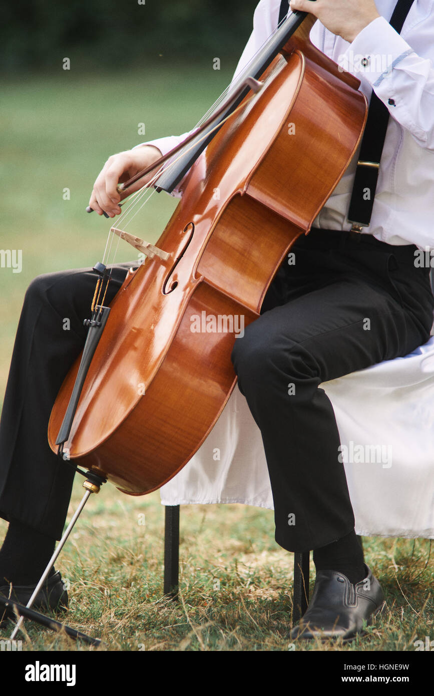 Joven tocando el violonchelo en el exterior. La violonchelista tocando música clásica en el cello Foto de stock