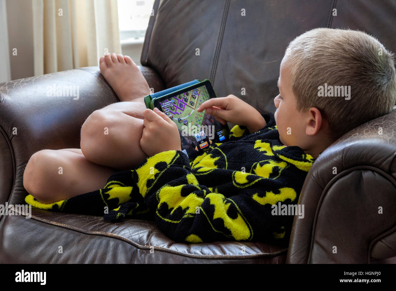 Niño de siete años jugando un juego en el iPad. Foto de stock