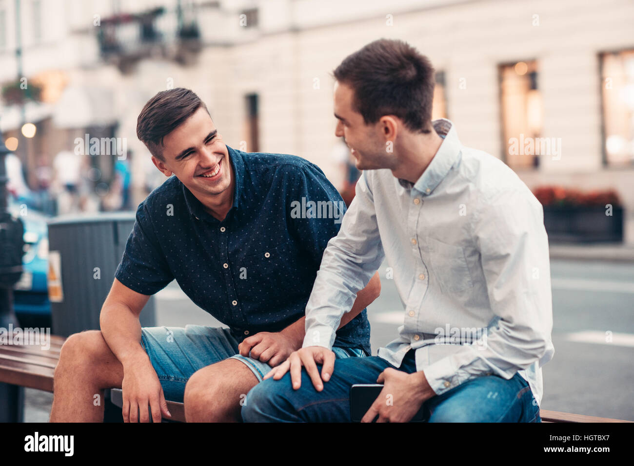 Amigos charlando en un banco en la ciudad Foto de stock
