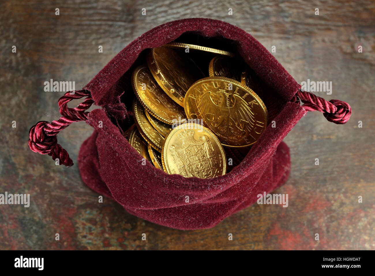 Circulación Europeo varias monedas de oro de la 19ª/20ª siglo en un bolso de terciopelo sobre fondo de madera rústica Foto de stock