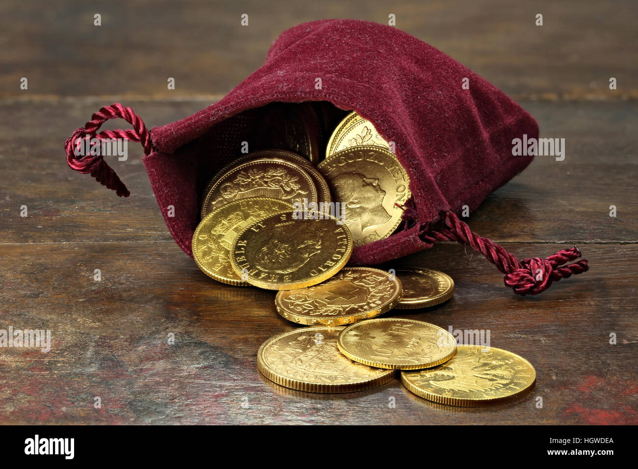 Circulación Europeo varias monedas de oro de la 19ª/20ª siglo en un bolso de terciopelo sobre fondo de madera rústica Foto de stock