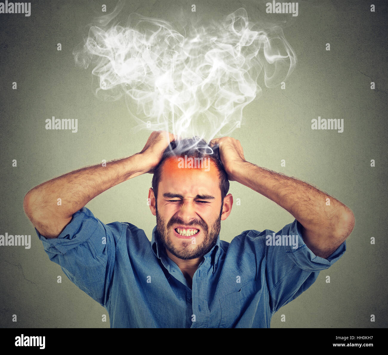 Destacado hombre teniendo dolores de cabeza saliendo vapor aislado sobre  fondo de pared gris Fotografía de stock - Alamy