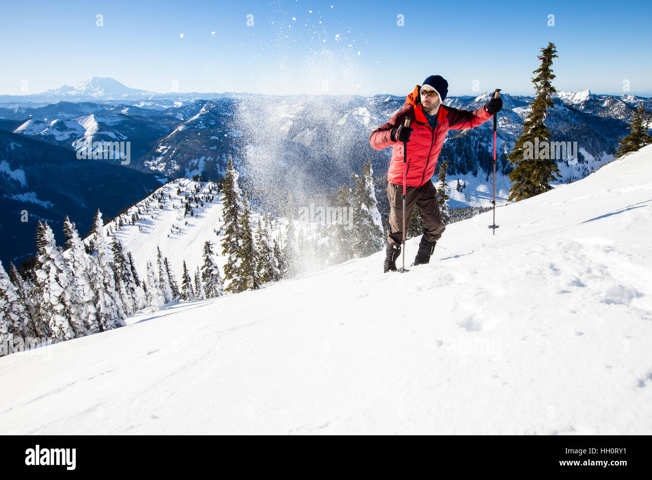 Un hombre subiendo una montaña con raquetas de nieve en las montañas Cascadas del norte del estado de Washington. Foto de stock