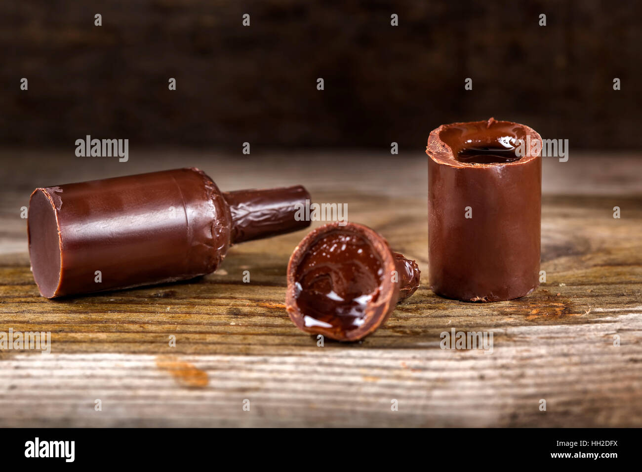 Dulces de Chocolate en forma de botella llena de sabores licor sobre fondo de madera Foto de stock