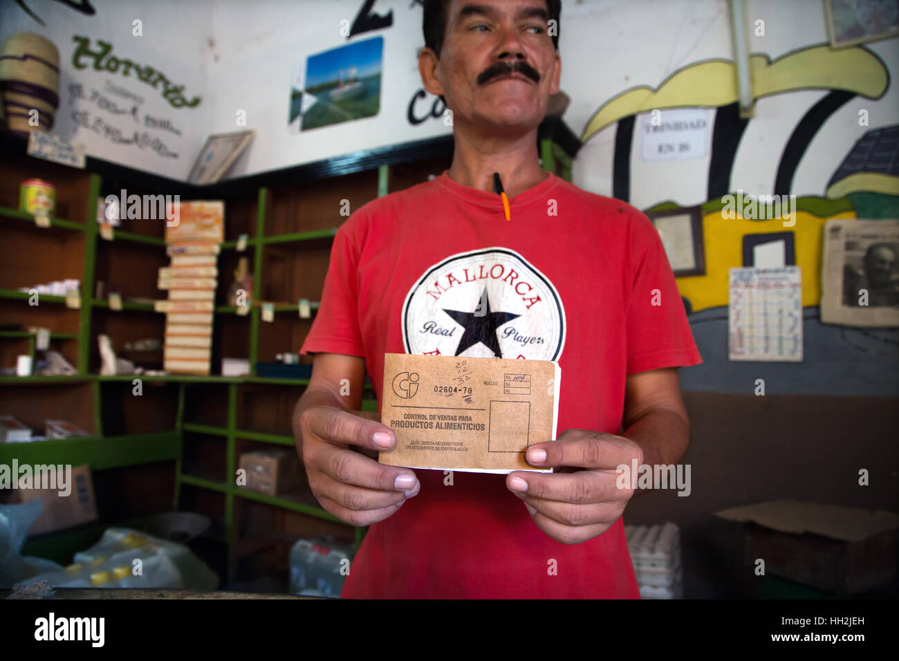 Un hombre está mostrando una "Libreta de abastecimiento" ("folleto consumibles") en una tienda de ultramarinos en Trinidad. Foto de stock