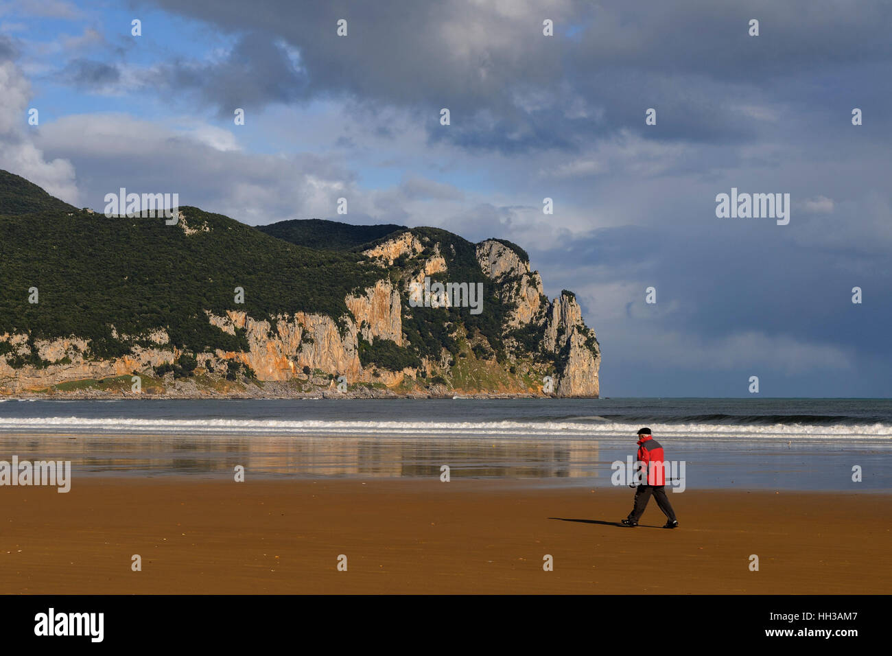 Hombre caminando por la playa de la localidad de Laredo, en la provincia de Cantabria, España, Europa. Foto de stock