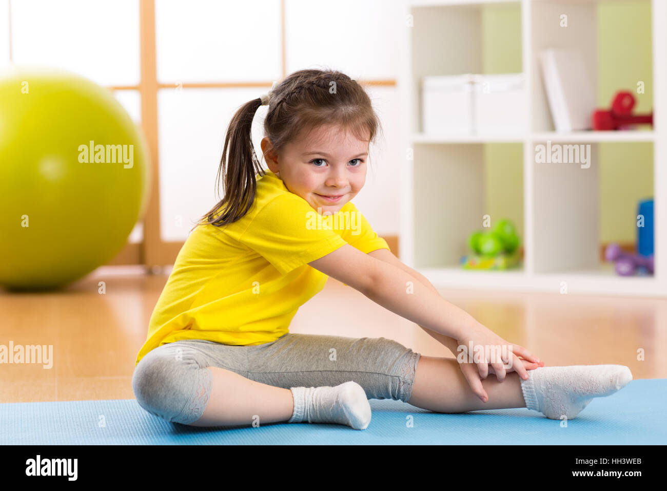 Kid haciendo ejercicios de gimnasia en casa en su habitación Foto de stock