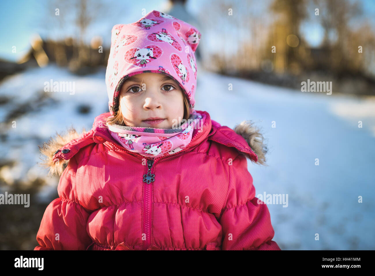 Niña en ropa de invierno de pie en mountain ski resort. Un niño con gorro,  bufanda y chaqueta de invierno está mirando la cámara fuera en snowy nat  Fotografía de stock -